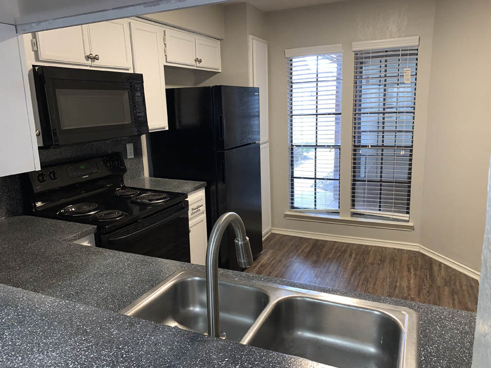 a kitchen with a sink and a black refrigerator