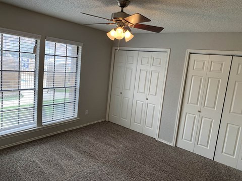 a living room with a ceiling fan and two windows