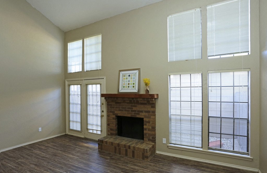 an empty living room with a fireplace and windows