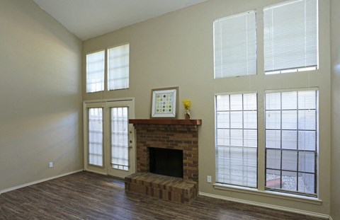 an empty living room with a fireplace and windows