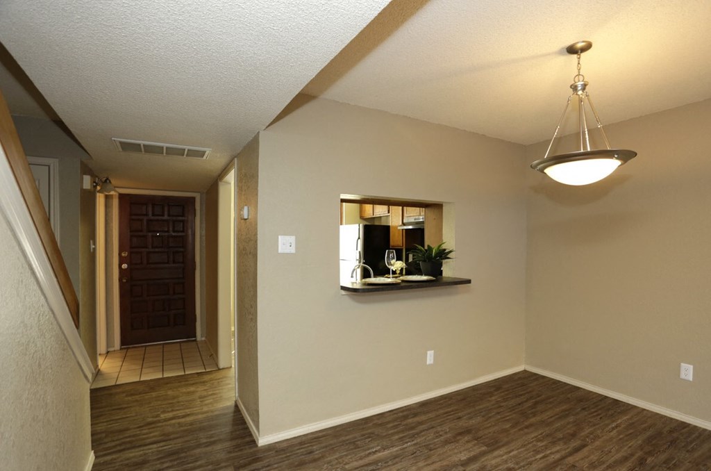 an empty living room with a hallway to a door and a mirror