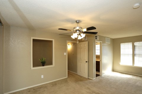 an empty living room with a ceiling fan