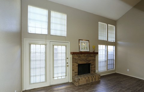 an empty living room with a fireplace and doors