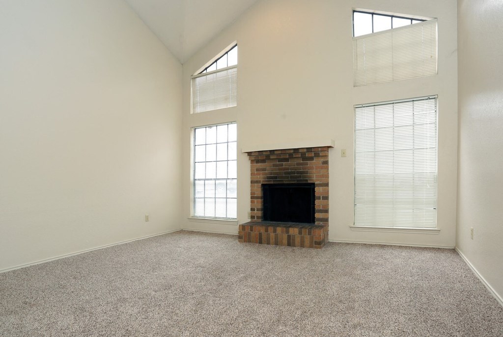 an empty living room with a fireplace and windows