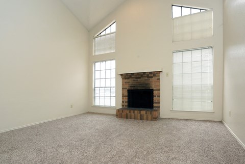 an empty living room with a fireplace and windows