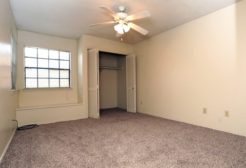 an empty living room with a ceiling fan and a closet