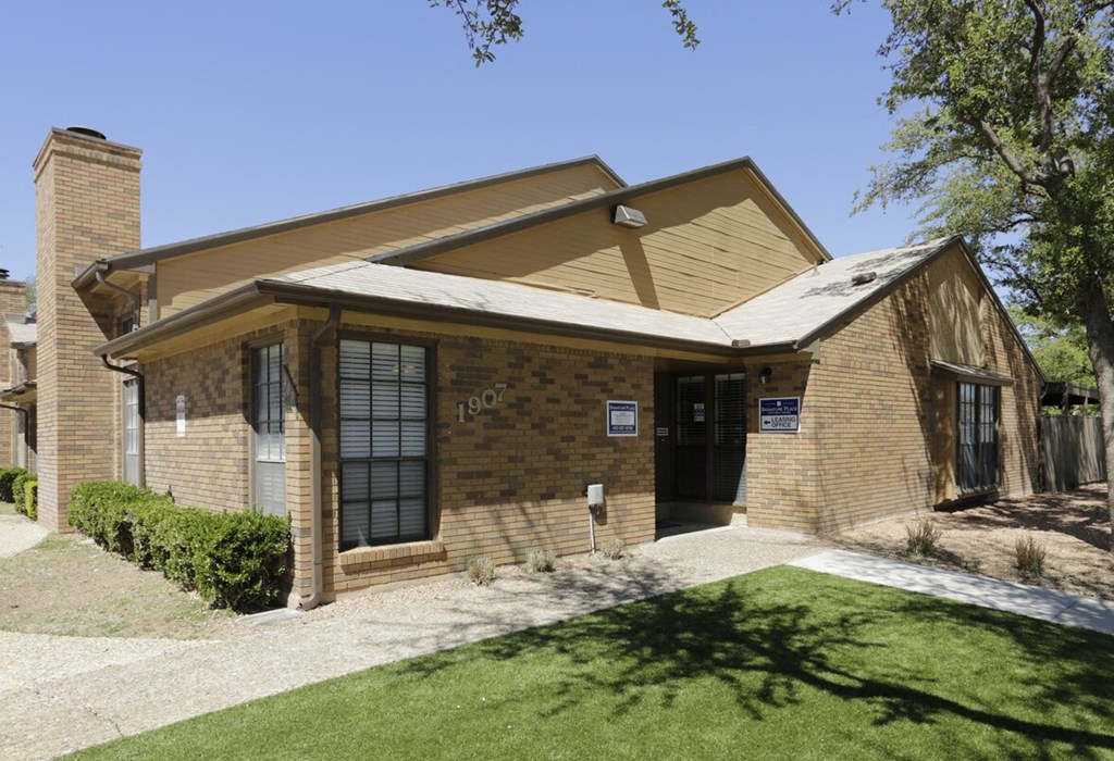 the front of a brick house with a driveway and lawn