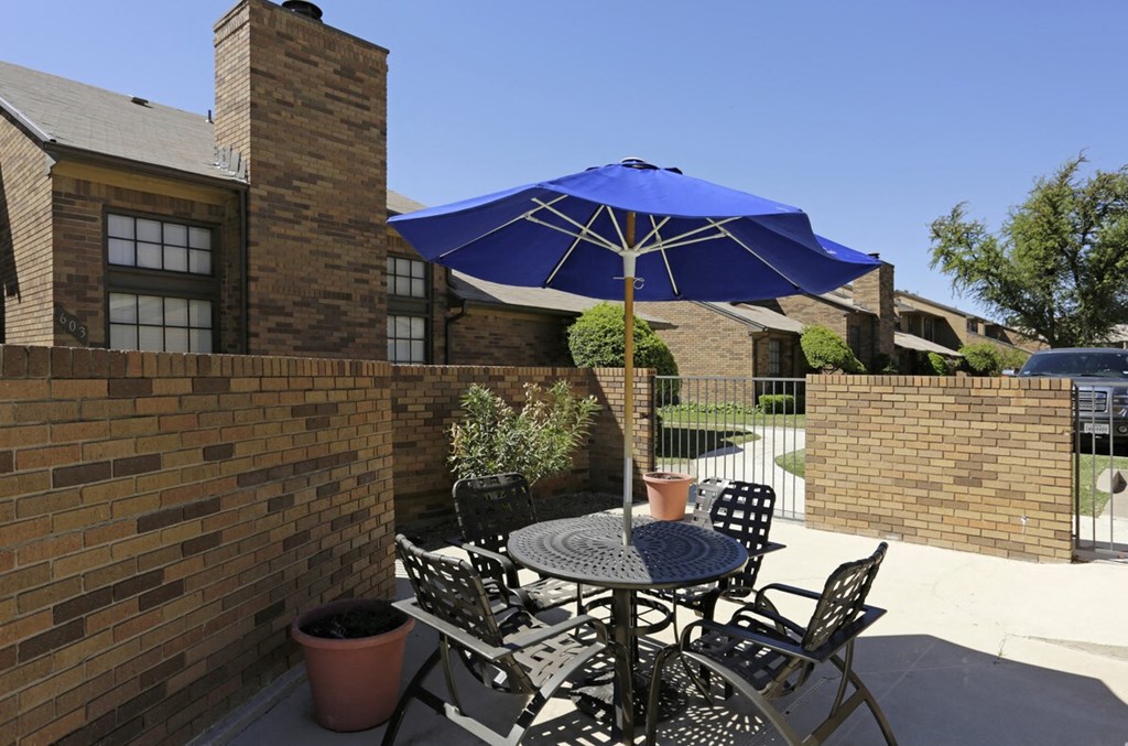 a patio with a table and chairs under an umbrella