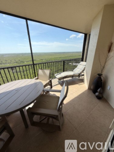 A balcony with a table and chairs overlooking a landscape.