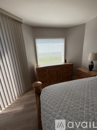 A bedroom with a bed, nightstand, and window with blinds.