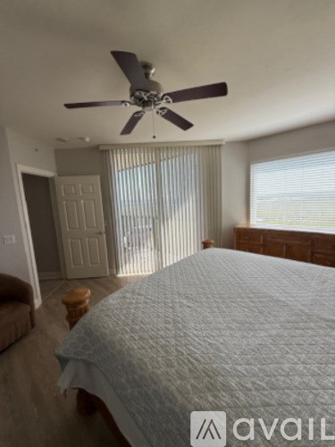 A bedroom with a large bed and a ceiling fan.