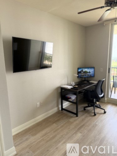 A room with a desk and a television mounted on the wall.