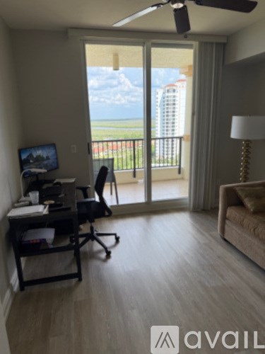 A room with a desk and a chair with a window overlooking a field.