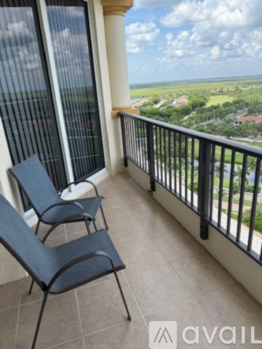 Two chairs are on a balcony overlooking a view.