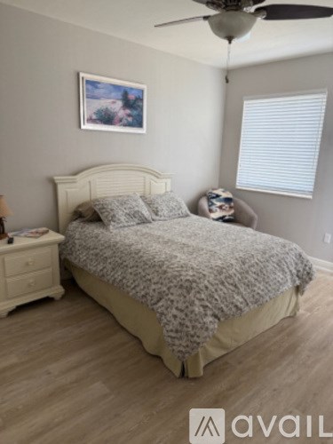 A bedroom with a bed, a dresser, and a ceiling fan.