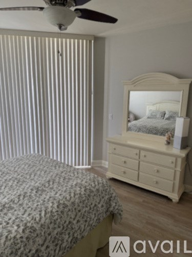 A bedroom with a bed, a dresser, and a ceiling fan.