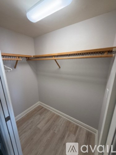 A small, empty closet with a wooden shelf and a white door.