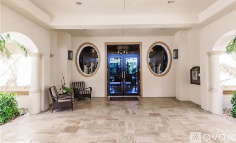 A foyer with a black chair and two round mirrors on the wall.