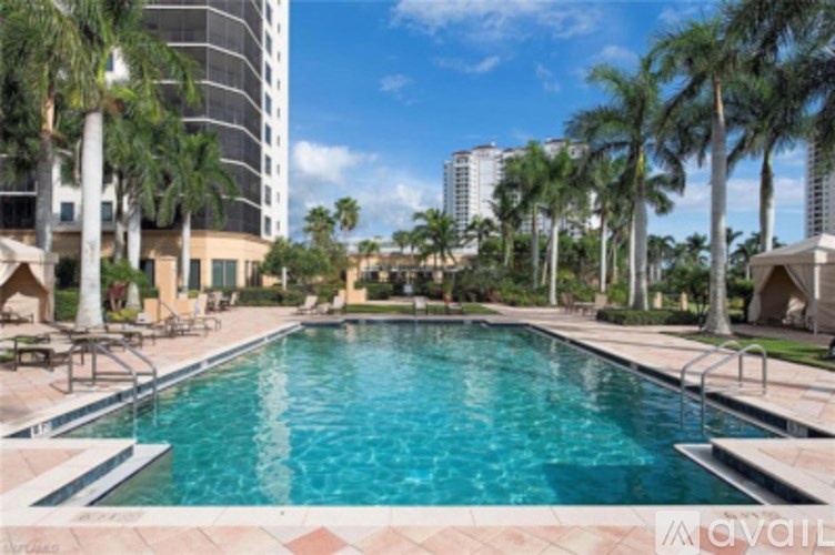 A large swimming pool surrounded by palm trees and lounge chairs.