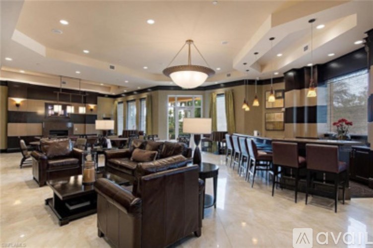 A spacious living room with brown leather furniture and a large chandelier.