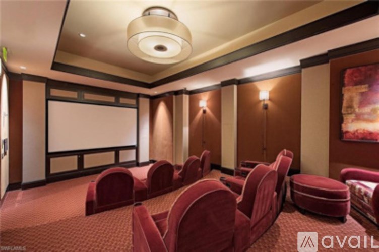 A cinema room with red seats and a screen.