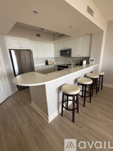 A kitchen with white cabinets and a bar area with stools.