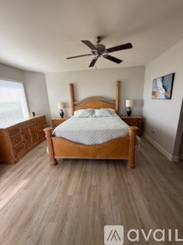 A bedroom with a large bed and a ceiling fan.