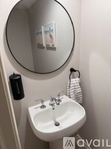 A white sink with a round mirror above it.