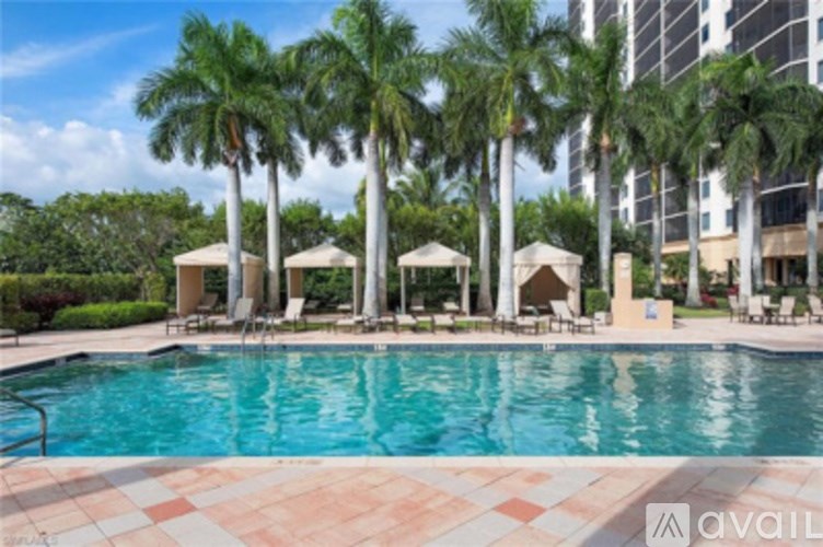 A pool surrounded by palm trees and lounge chairs.