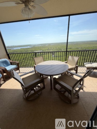 A patio with a table and chairs overlooking a field.
