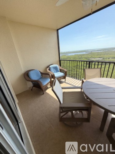 A balcony with a table and chairs overlooking a body of water.
