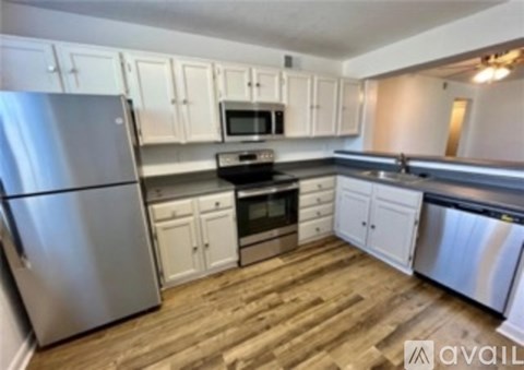 A kitchen with white cabinets and a wooden floor.