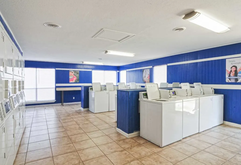 a group of white washing machines in a room with blue walls