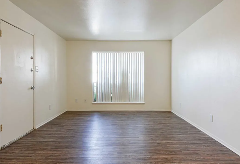 an empty living room with a window and wooden floors