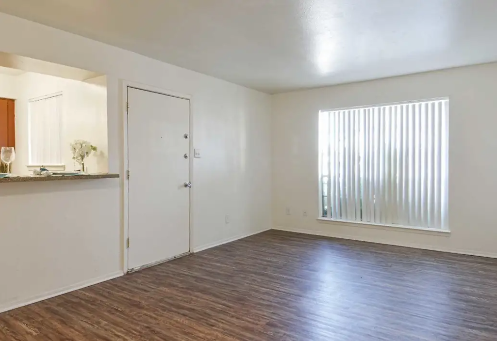 an empty living room with white walls and a large window