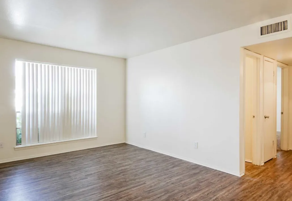 an empty living room with a window and wood flooring