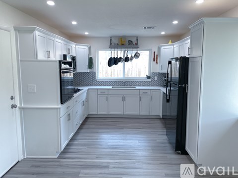 A kitchen with white cabinets and a black refrigerator.