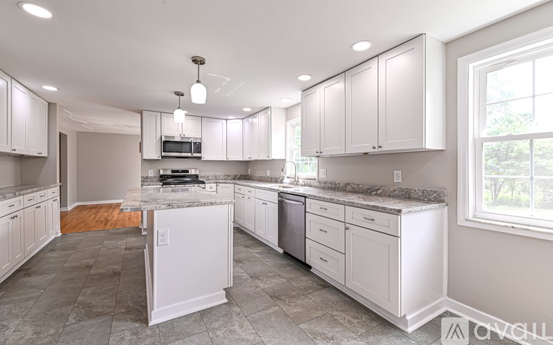 A kitchen with white cabinets and a marble countertop.