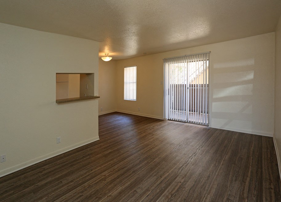 an empty living room with wood flooring and a window
