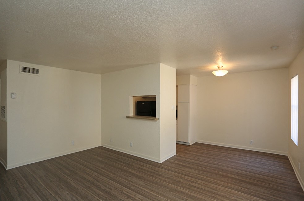 an empty living room with wood flooring and white walls