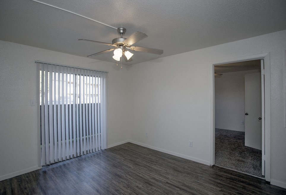 an empty living room with a ceiling fan and a window