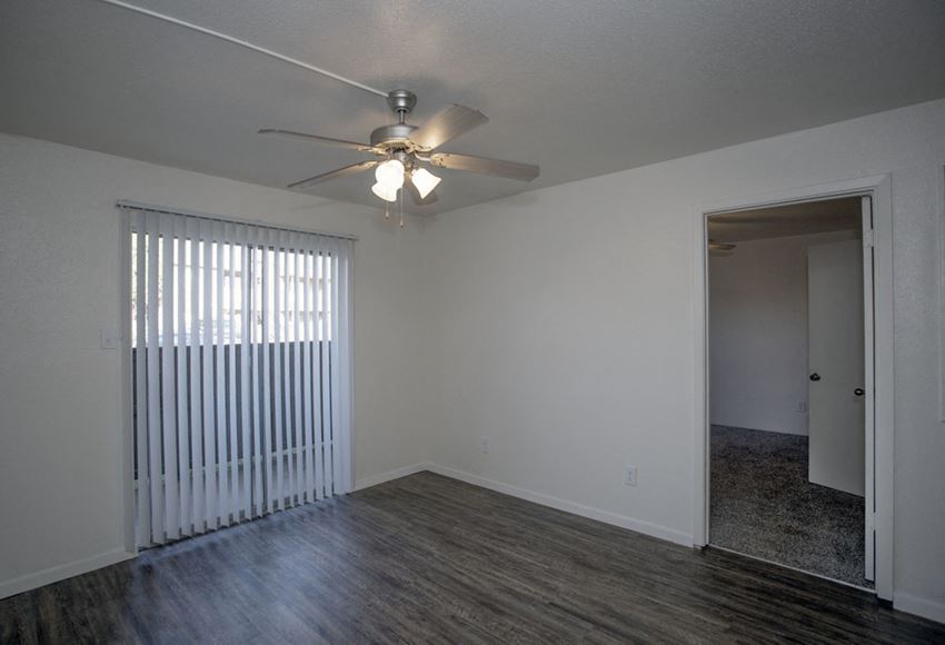 an empty living room with a ceiling fan and a window