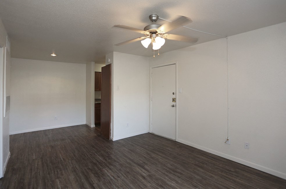 the living room of an empty apartment with a ceiling fan