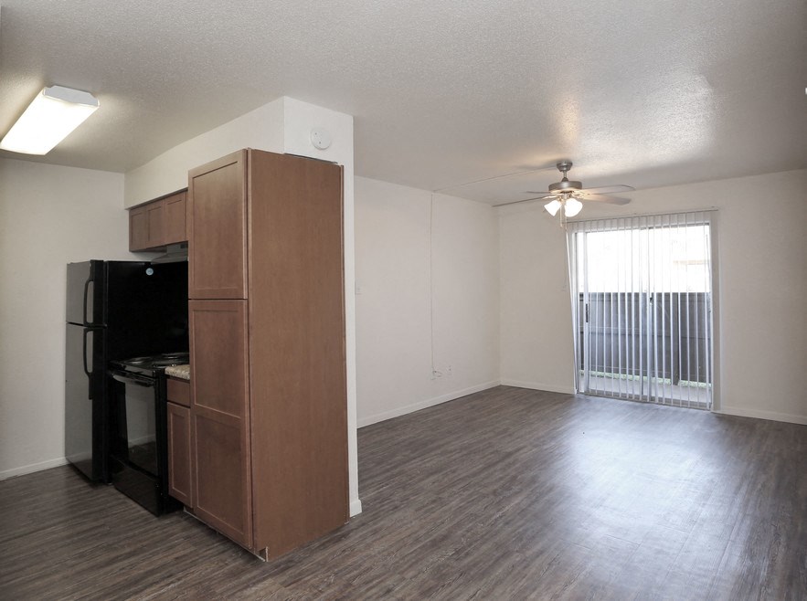 an empty living room and kitchen with a refrigerator and a