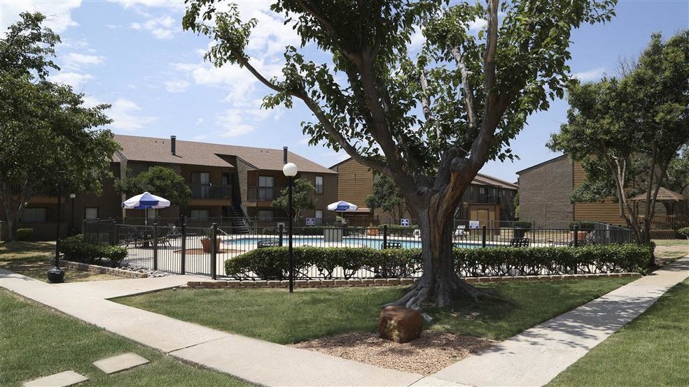 a tree in a yard in front of a pool