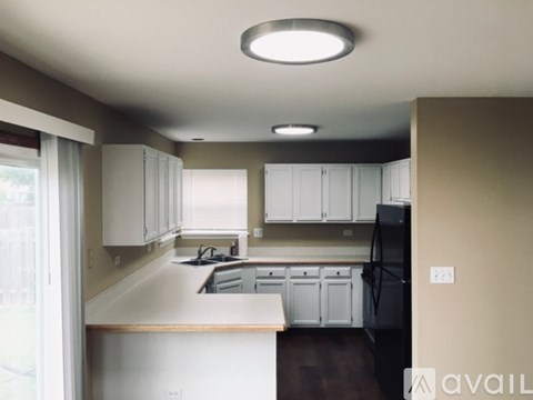 A kitchen with white cabinets and a black refrigerator.