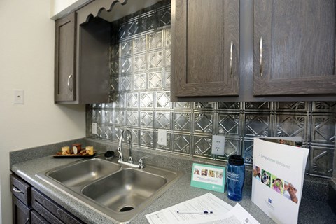 a kitchen with a sink and cabinets and a paper on the counter