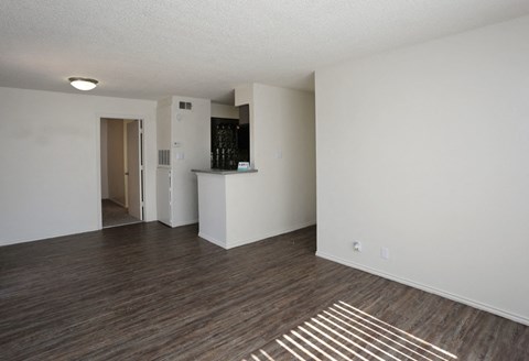 an empty living room with wood flooring and white walls