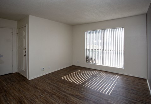 an empty living room with wood flooring and a window
