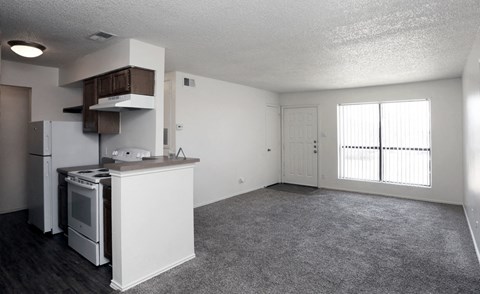 an empty kitchen and living room with a stove and refrigerator